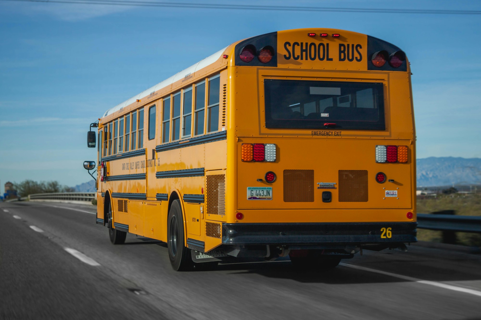 Rear view of a yellow American school bus with SCHOOL BUS decal lettering and emergency exit markings